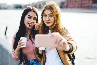 Akıllı telefon kamerasında fotoğraf çeken güzel genç bir kadın sokakta kahve içmek için boş zaman harcıyor. Cep telefonuyla blog yazmak için poz veren hippi kadınlar.