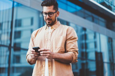 30 'lu yaşlarda beyaz bir adam şehir ortamında dikilirken iş arkadaşlarıyla sohbet ediyor. Normal gömlekli yakışıklı bir erkek, cep telefonundan 4G' ye bağlanan bir uyarı mesajı veriyor.