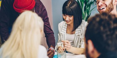 Genç, çok ırklı erkek ve kadın öğrenciler, dost atmosferde işbirliği yaparken eğleniyorlar, neşeli refah içinde çalışanlar beyin fırtınası yapıyorlar, yaratıcı fikirleri paylaşıyorlar ve ofiste konuşuyorlar.