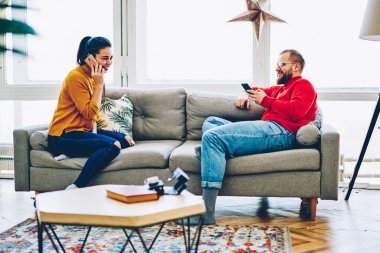 Kafkasyalı mutlu bir kadın cep telefonuyla sohbet ediyor ve erkek arkadaşı akıllı telefonla ev kablosuz bağlantısından memnun, mutlu bir çift dairede modern teknolojiyi kullanıyor.