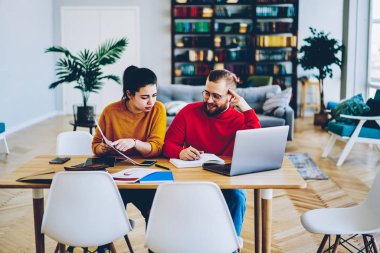 Genç bayan, birlikte sınavlara hazırlanan zeki erkek arkadaşa danışmanlık yapıyor. Masaüstünde oturan beyaz bir kadın özel ders alıyor. Öğrenme ve muhasebe eğitimi alıyor.