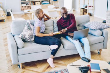 Neşeli Afrikalı evlilikleri evde boş zamanlarında oturma odasındaki rahat koltukta oturup eğleniyor. Aşık çift şakalaşıyor ve konuşuyor. Bu arada erkek dizüstü bilgisayarını kullanıyor ve kadın da Rea için kitap tutuyor.