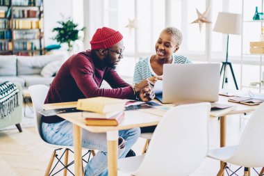 Modern iç mekanda masaüstünde oturan yaratıcı fikirleri ve planları tartışan meslektaşlar, Apartman dairesinde dizüstü bilgisayar kullanarak iletişim kurmayı öğrenen ve kullanan Afro-Amerikan öğrenciler
