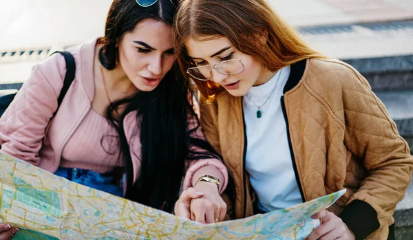 专心致志的嬉皮士女孩们阅读地图 把重点放在位置规划路线和讨论想法上 看着目的地旅行的高加索女游客们一起谈论旅游 — 图库照片
