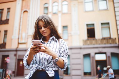 Açık havada cep telefonuyla gezen 4G internete bağlı beyaz bir kadın. Genç hippi kız, sosyal ağlardaki takipçilerle telefon görüşmeleri yaparak mesajlar gönderiyor.