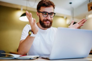 Gözlüklü, gülümseyen hippi, online yarışmayı kazanmaktan mutlu. Dizüstü bilgisayardan bildirimi kontrol ediyor. Kafkasyalı, serbest çalışan, online kazançlardan memnun.