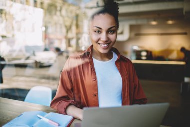 Mutlu kız öğrenci portresi e-öğrenim için çalışma alanında zaman harcıyor ve kolej dersi için bilgi araştırması yapıyor modern dizüstü bilgisayarla oturuyor, otodiktat konsepti