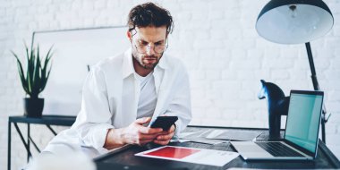 Kafkas erkek serbest bankacı evden çalışan cep telefonundaki bakiyeyi kontrol ediyor, apartman dairesinde hippi adam uzaktan kumandalı Jo 'da işlem yapmak için akıllı telefon kullanıyor.