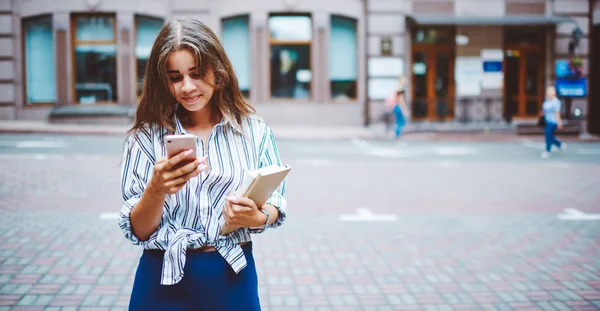 Çekici kız öğrenci cep telefonundan gelen yeni mesajları kontrol ediyor sokakta geziniyor, pozitif hippi kız 4G bağlantısını kullanarak arkadaşlarıyla cep telefonuyla sohbet ediyor.