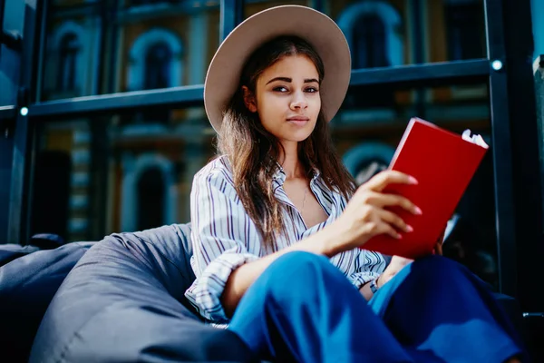 Mujer Seria Sombrero Moda Mirando Cámara Sentada Con Libro Que — Foto de Stock