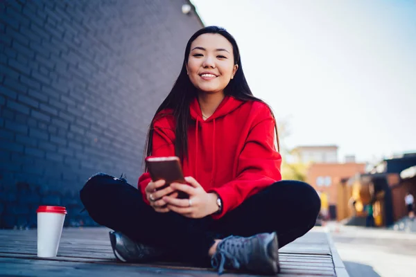 Portret Szczęśliwej Chińskiej Hipsterki Smartfonem Ręku Uśmiechniętym Aparatu Czekającej Przyjaciela — Zdjęcie stockowe