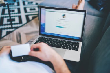 Kredi kartı tutan adamın evdeki kablosuz internete bağlı dizüstü bilgisayarla çevrimiçi para transferi yaparken çekilmiş resmi, erkek kullanıcı netbook üzerinden web mağazalarından alışveriş yapıyor