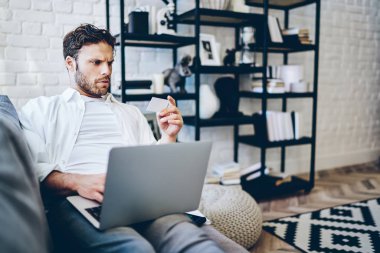 Düşünceli Kafkasyalı adam bilgisayarla ve kablosuz internetle alışveriş yapmak için evden bilgi toplamaya odaklanmış. Ciddi hippi adam kredi kartı numarasıyla Netbook 'ta işlem yapıyor.