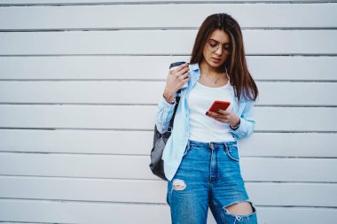 Siyah sırt çantalı genç bir kadın kırmızı akıllı telefon tutuyor ve 4G interneti kullanarak cihazdan e-posta kontrol ediyor. Promosyon arka planında cep telefonuyla takipçilerle sohbet eden bir blog yazarı.