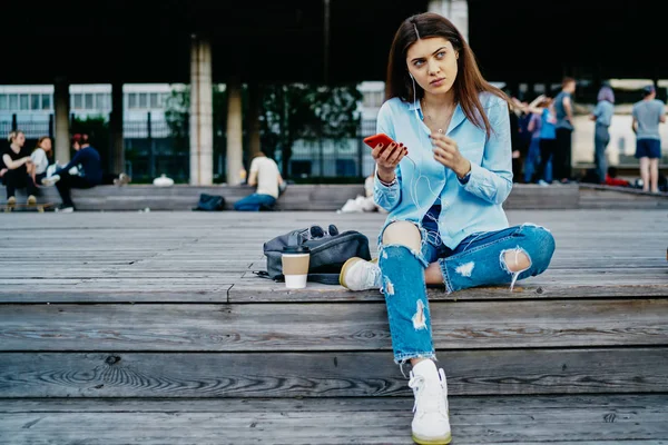 Çekici Genç Bir Kadın Dışarıda Oturmuş Akıllı Telefon Cihazına Indirilmiş — Stok fotoğraf