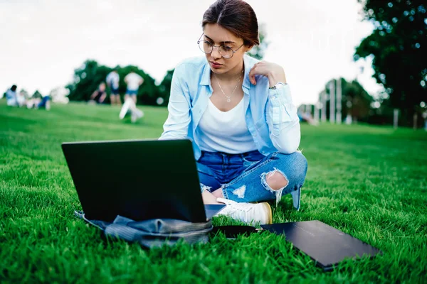 Pensive Young Woman Eyeglasses Watching Tutorial Online Website Sitting Green — Stock Photo, Image