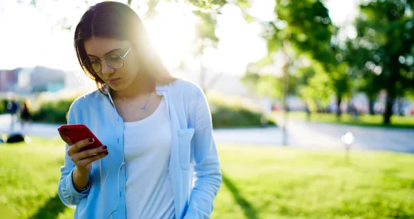 スタイリッシュな服装のヒップスターの女の子は 都市部の設定で4Gインターネット接続を介してオーディオをダウンロードする携帯電話上の音楽アプリを更新します — ストック写真