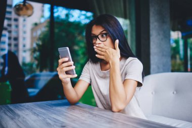 Şok olmuş Kafkas ergen hippi kız akıllı telefondan iyi haberler okuyor, mutlu duygusal genç kadın web mağazasındaki satışlardan şaşkına dönüyor ve cep telefonundan indirim ve uyarı alıyor.