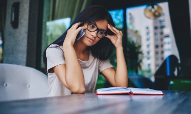 Gözlüklü, düşünceli, beyaz kadın cep telefonu çözme sorunu hakkında ciddi bir konuşma yapıyor. Düşünceli hippi kız, bakiyeyi ve krediyi kontrol etmek için banka operatörünü arıyor.