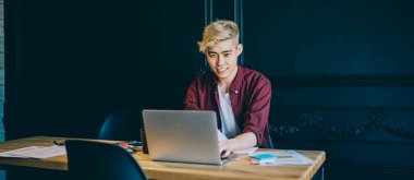 Pozitif genç adam Çin dizüstü bilgisayarında kablosuz internet bağlantısı kullanarak yazılımı güncelliyor. Günlük giyinmiş neşeli Japon hipster öğrenci internette komik webinar izlerken gülüyor.