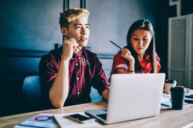 Düşünceli Çinli hippi, yaratıcı fikirler üretiyor kendi internet sitesini kuruyor Japon meslektaşıyla birlikte modern uzayda dizüstü bilgisayarın başında oturuyor ve kablosuz internet kullanıyor.
