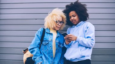 Boş zamanlarını birlikte geçirirken mobil uygulama bildirimini kontrol eden kadın blogcular, cep telefonundan 4G kablosuz internet sitesine bağlı hipster arkadaşlar bilgi okuyorlar