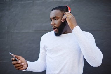 İnternet 'ten müzik indirmek için internet sitesinden müzik seçen hayret verici bir adam yüksek hızdaki internetten şok geçiriyor, internetten sohbet ederken kulaklıkla cep telefonlarına bağlı şarkılar dinleyen harika bir adam.