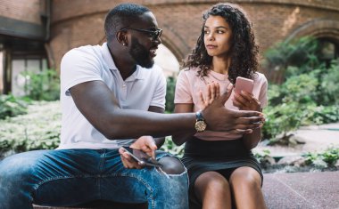 Kıvırcık saçlı Afro-Amerikalı hippi kız kıskanç erkek arkadaşından akıllı telefon aygıtı saklıyor ihanetinden şüpheleniyor online sohbet, ilişki kavramı ve aşk sırlarını okumaya çalışıyor.