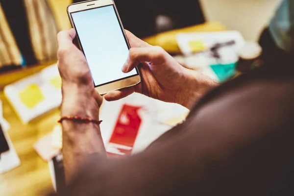 Cropped image of guy holding mobile phone with mock up screen sending text message using application, millennial man using smartphone and browsed website for share multimedia content onlin