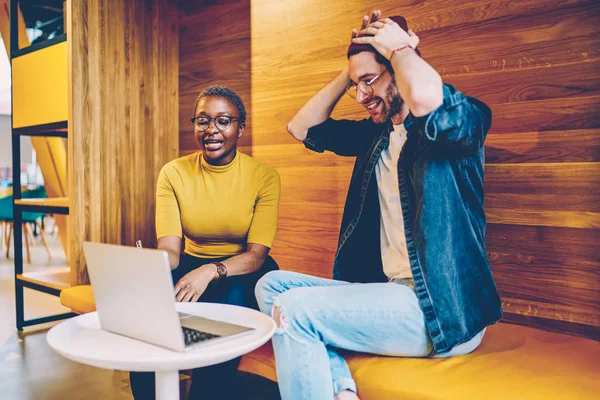 Qualified african american teacher explaining stupid mistake done by skilled hipster student on video presentation on modern laptop computer during private lesson in coworking space