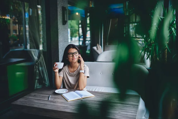 Молодая Привлекательная Женщина Очках Которая Разговаривает Телефону Сидя Ноутбуком Кафе — стоковое фото