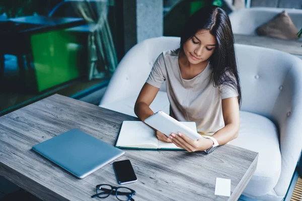 Mujer Morenita Concentrada Anotando Información Cuaderno Usando Portátil Para Investigación —  Fotos de Stock