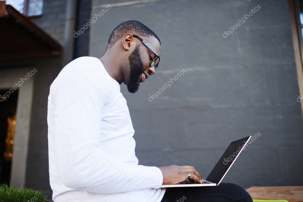 Side view of skilled male freelancer working remotely with startup project using 4g wireless connection on laptop computer during time for distance job, concept of technology and communication