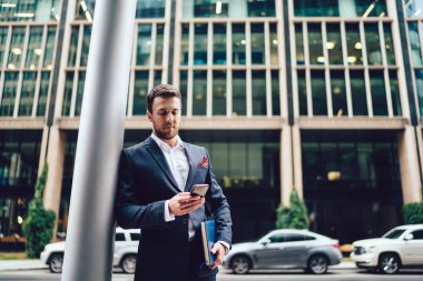 Resmi olarak akıllı erkek girişimci, finans bölgesinde şehir merkezinde ayakta duran cep telefonu aygıtı, iş hayatı ve iletişim konsepti ile posta denetimi yapıyor.
