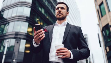 Şehir merkezinde resmi olarak giyinmiş işadamlarının elinde cep telefonu ve kahveyle durup düşünceli bakışlarını çevirmesi ve şehir merkezinde akıllı telefonlu düşünceli bir finans uzmanı olması görüşünün altında.