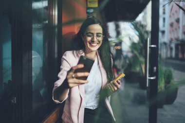 Sıradan giyinen mutlu İspanyol kadın cep telefonu cihazıyla selfie çektirirken kameraya gülümseyen neşeli hippi kız boş zamanlarının tadını çıkarırken fotoğraf çektiği için kameraya gülümsüyor.