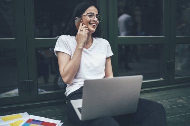 Fotokopi alanı tişörtlü heyecanlı hipster programcı arkadaşça akıllı telefon görüşmeleri sırasında gülüyor. Uzak iş sırasında ilginç bir web sitesi yaratmak için başlangıç grafik projesi ile iyi haberlerin tadını çıkarıyor.