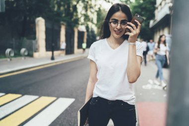 Tasarım için tasarım kitabı olan çekici bir kız öğrenci kameraya bakarken cep telefonu uygulaması aracılığıyla sesli mesaj alıyor. Milenyum insanının yarım boy portresi.