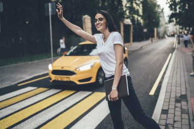 Daha iyi görebilmek için gözlüklü genç ve çekici bir kadın taksiyi durdurmak için yolun kenarında dikilirken, güzel Gürcü hippi kız açık havada toplu taşıma araçlarını yakalamaya çalışıyor.
