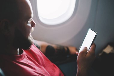 Uçağın kabin penceresinin yanında otururken kablosuz internete bağlanan genç adamın arka görüntüsü. İçerik web siteniz için boş ekranı, Uçak Çevrimdışı kipini oluşturun