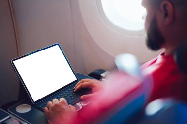 Uçaktaki kablosuz internete dokunmatik ped ile bağlanan genç bir uçuş yolcusu uçak kabin penceresinin yanında oturuyor. Web şablonu için boş ekranı, serbest ansiklopedideki dijital göçebe çalışmasını yapılandırName
