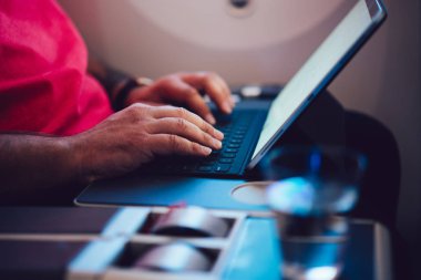 Uçaktaki kablosuz internete dokunmatik ped ile bağlanan genç bir uçuş yolcusu uçak kabin penceresinin yanında oturuyor. Ağ şablonu için boş ekranı, serbest çalışma için dijital göçebe işini düzenle