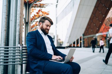 Resmi olarak giyimli iş adamı şehir ortamında oturuyor ve modern dizüstü bilgisayarda kamu İnternet kullanan girişimciler için sunum yapıyor, erkek tüccar denetimi başlatılıyor
