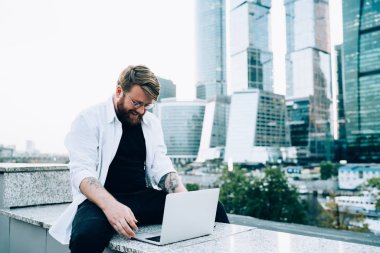 Neşeli sakallı bir adam kendi blog sayfasında yayınlamak için metin bilgileri yazıyor olumlu eleştiriler ve yorumlardan kendini iyi hissediyor, mutlu erkek serbest çalışan dizüstü bilgisayardaki internet sitelerini tarıyor.