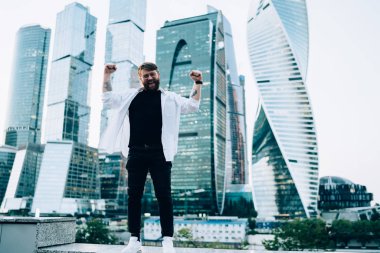 Yeni megalopolis 'i keşfettiği için uluslararası seyahati kutlayan neşeli erkek turistin tam boy portresi. Elleri havada başarılı bir Kafkas gezgini.