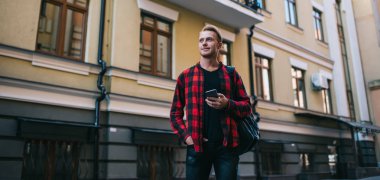 Akıllı telefonlu, kendinden emin bir adam başka tarafa bakıyor.