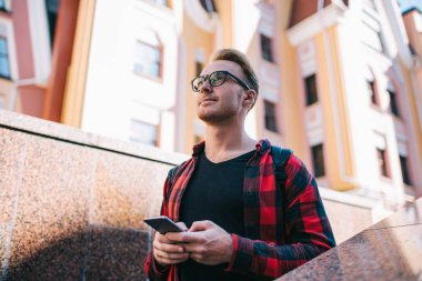 Sokakta akıllı telefon kullanan düşünceli bir adam.