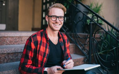 Neşeli adam merdivenlerden not alıyor.