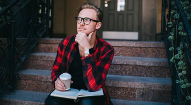 İçkili ve not defterli bir adam merdivenlerde düşünüyor.