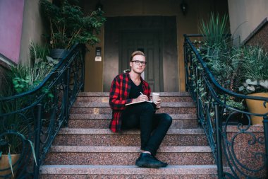 Evin dışında sıcak içecek yazan şık bir adam.